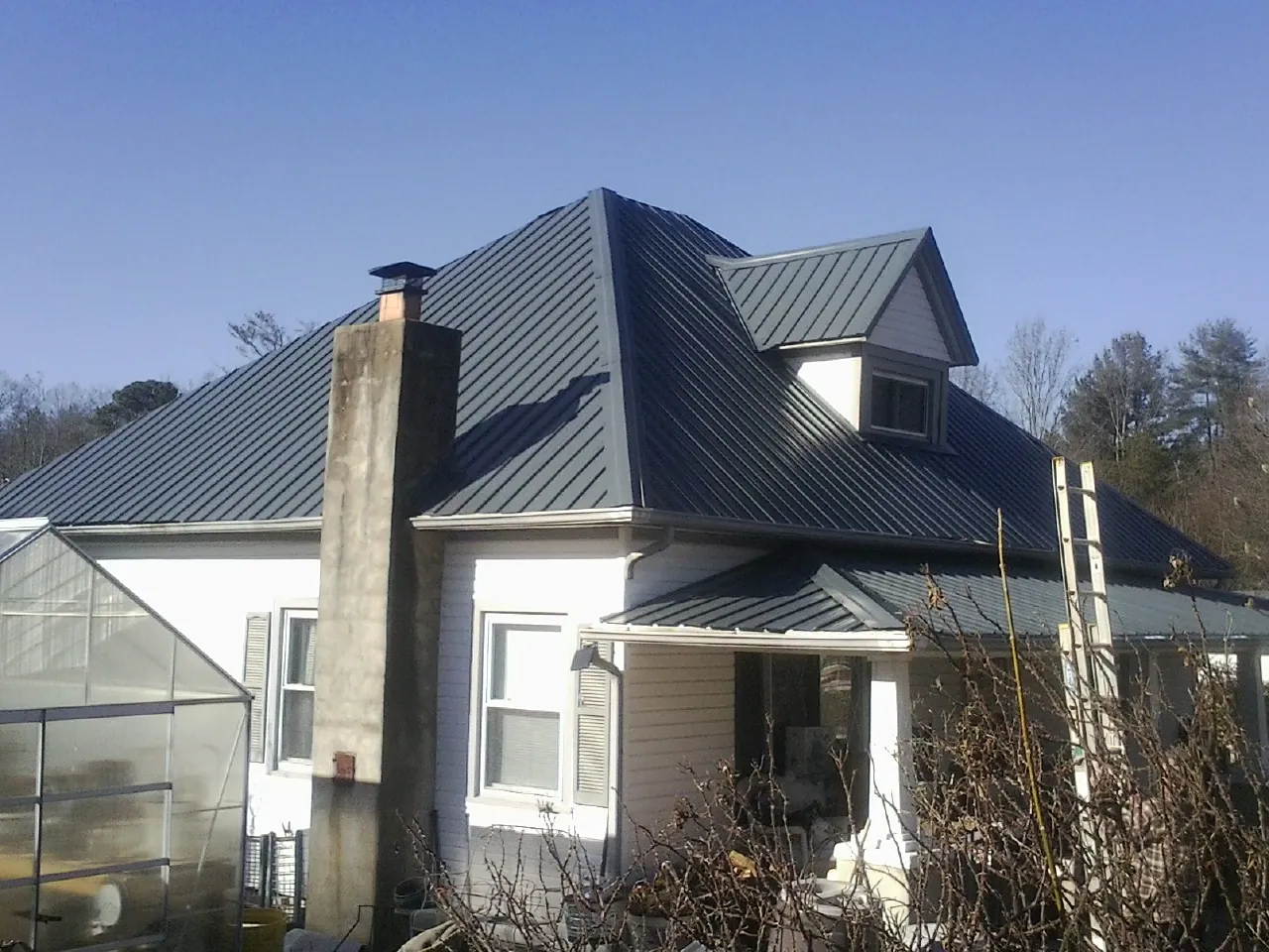 Dark blue standing seam metal roof on a white farmhouse with dormer — Slate & Tile Roof Repair by Roofing Brothers in Atoka
