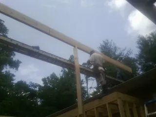 Carpenter setting a ridge beam over a new addition frame — Ice Dam Removal by Roofing Brothers in Atoka