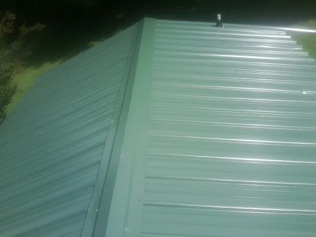 New green metal panels meeting at the ridge of a roof — Flat Roof Repair work by our crew in Atoka