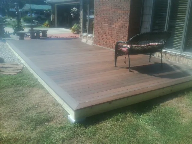 New wood deck and wicker chair beside a brick house in Atoka