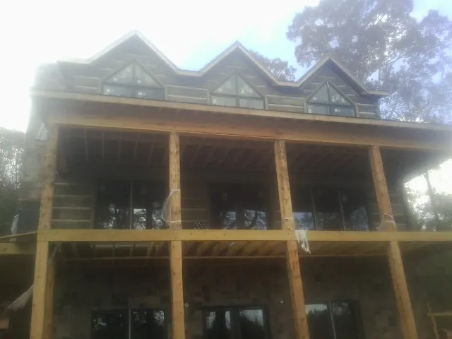 Dormers and porch framing on a large log home under construction — Roof Coating work by our crew in Atoka