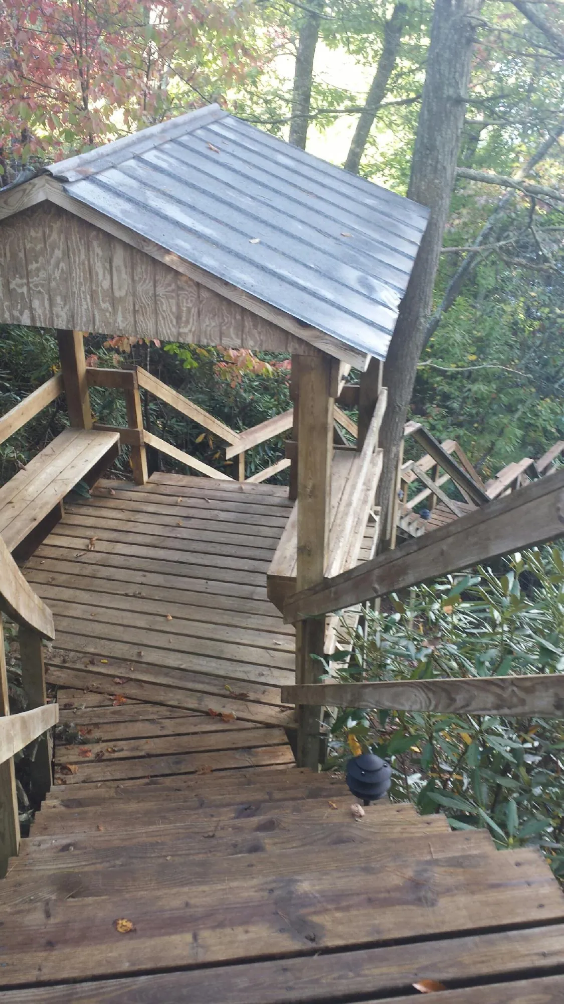Metal roofed shelter over wooden steps on a wooded walkway — Skylight Repair & Installation work by our crew in Atoka