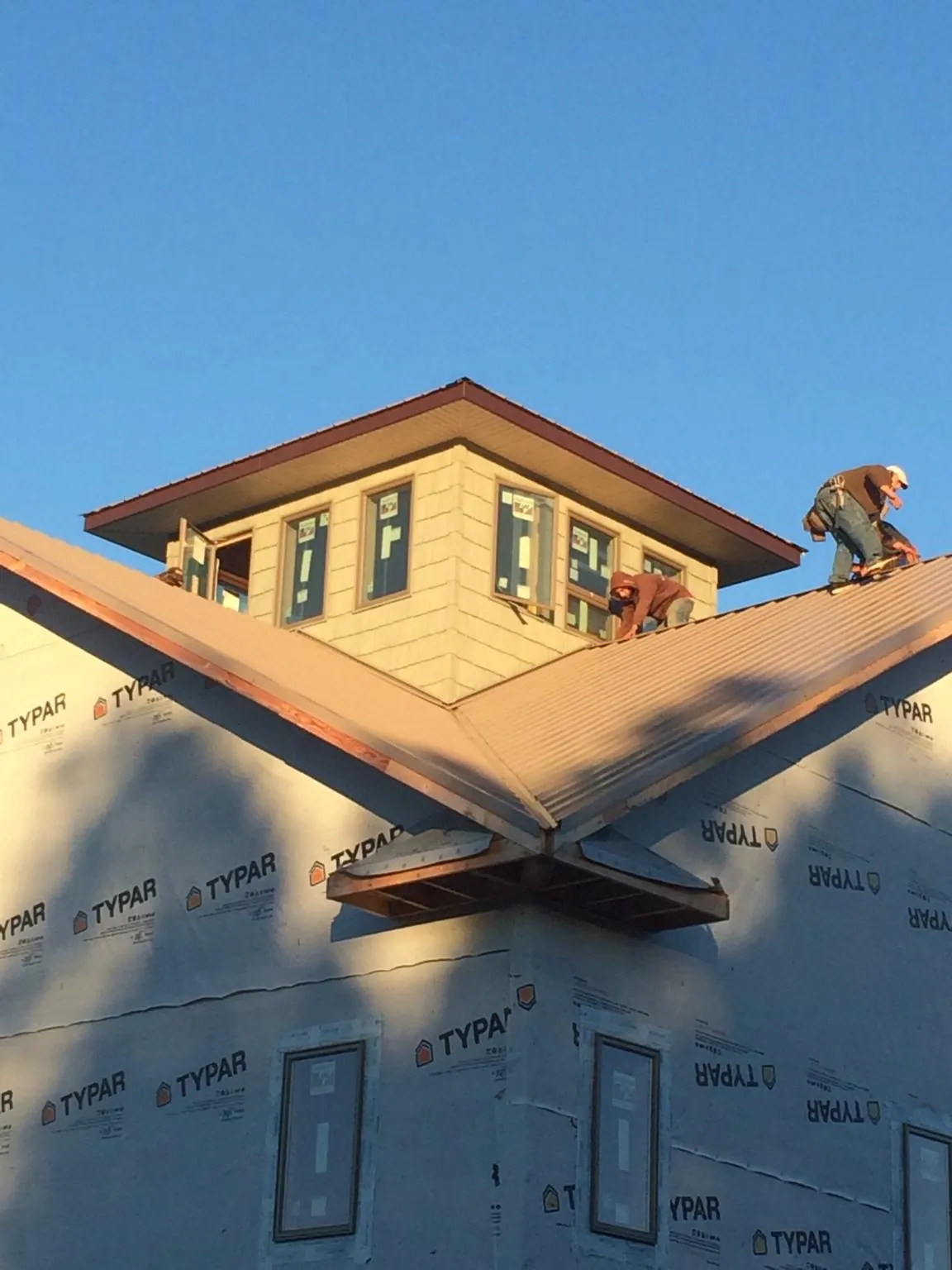 Roofers working around a rooftop cupola on a new metal roof at sunset — Roof Waterproofing in Atoka by Roofing Brothers